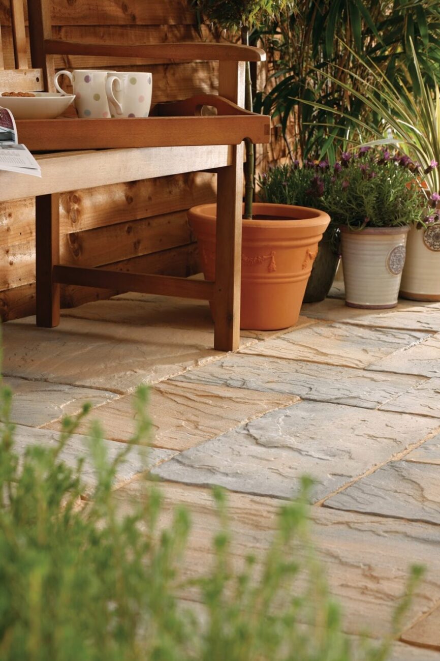 Bradstone garden paving, Ancestory Abbey Brown with pots, flowers, and bench for aggregate Industries, Studio photography by Ross Vincent
