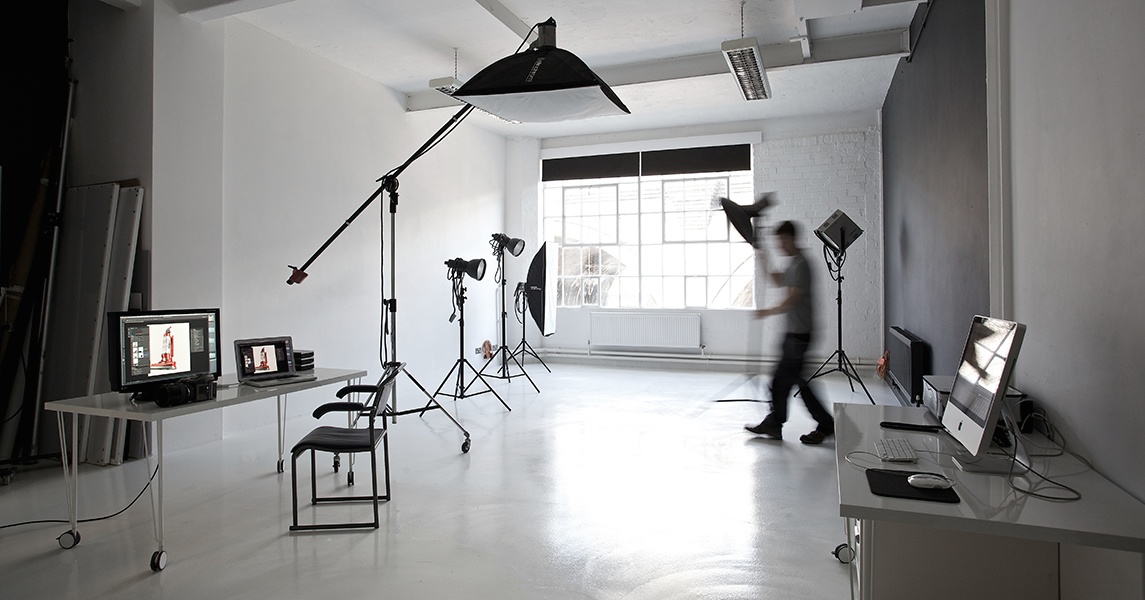 Photographic studio showing lights and computers with assistant moving stand