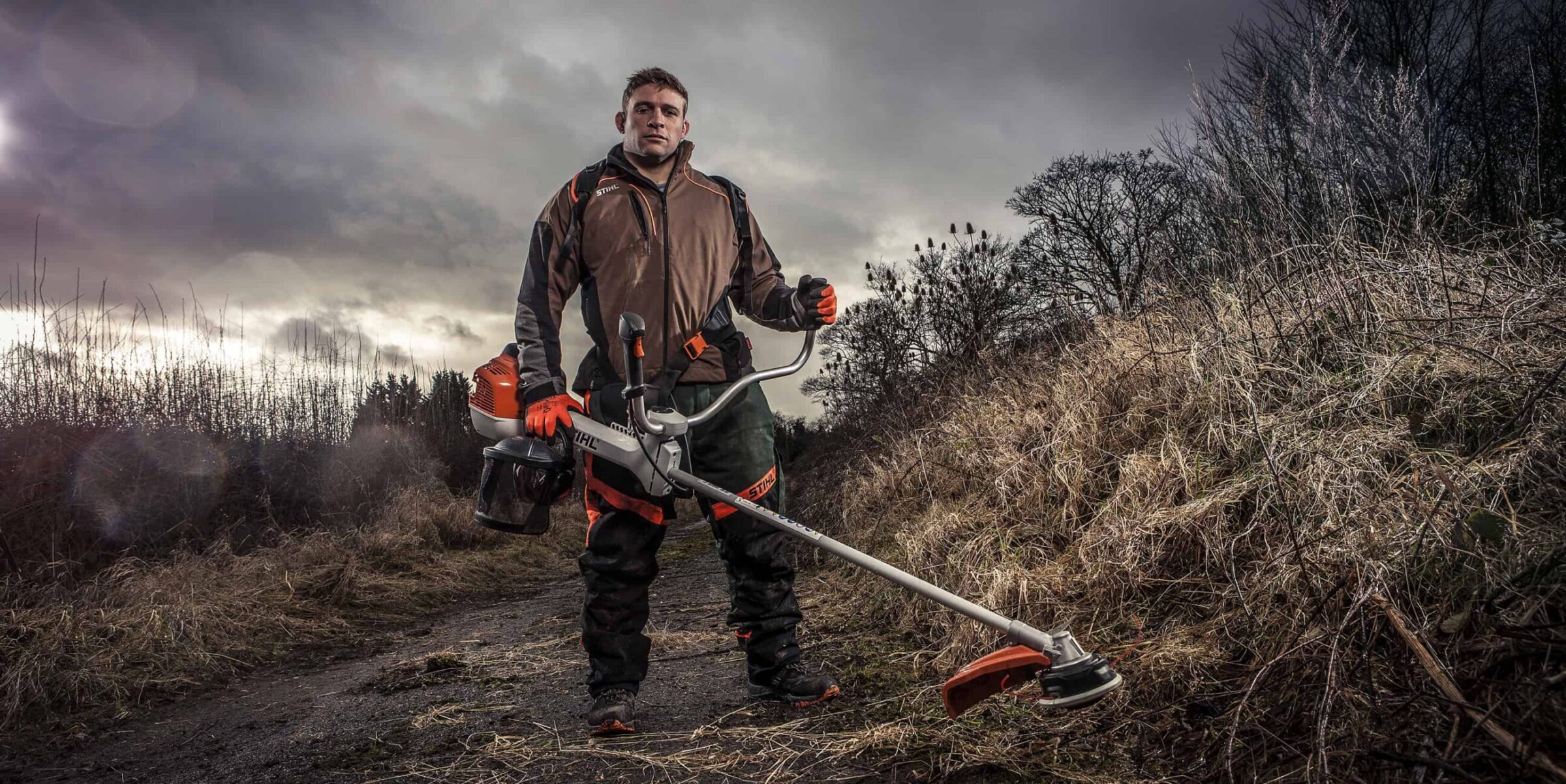 Tom Youngs Leicester Rugby Hooker using Stihl Brushcutter tool with storms, rain and dramatic Sky
