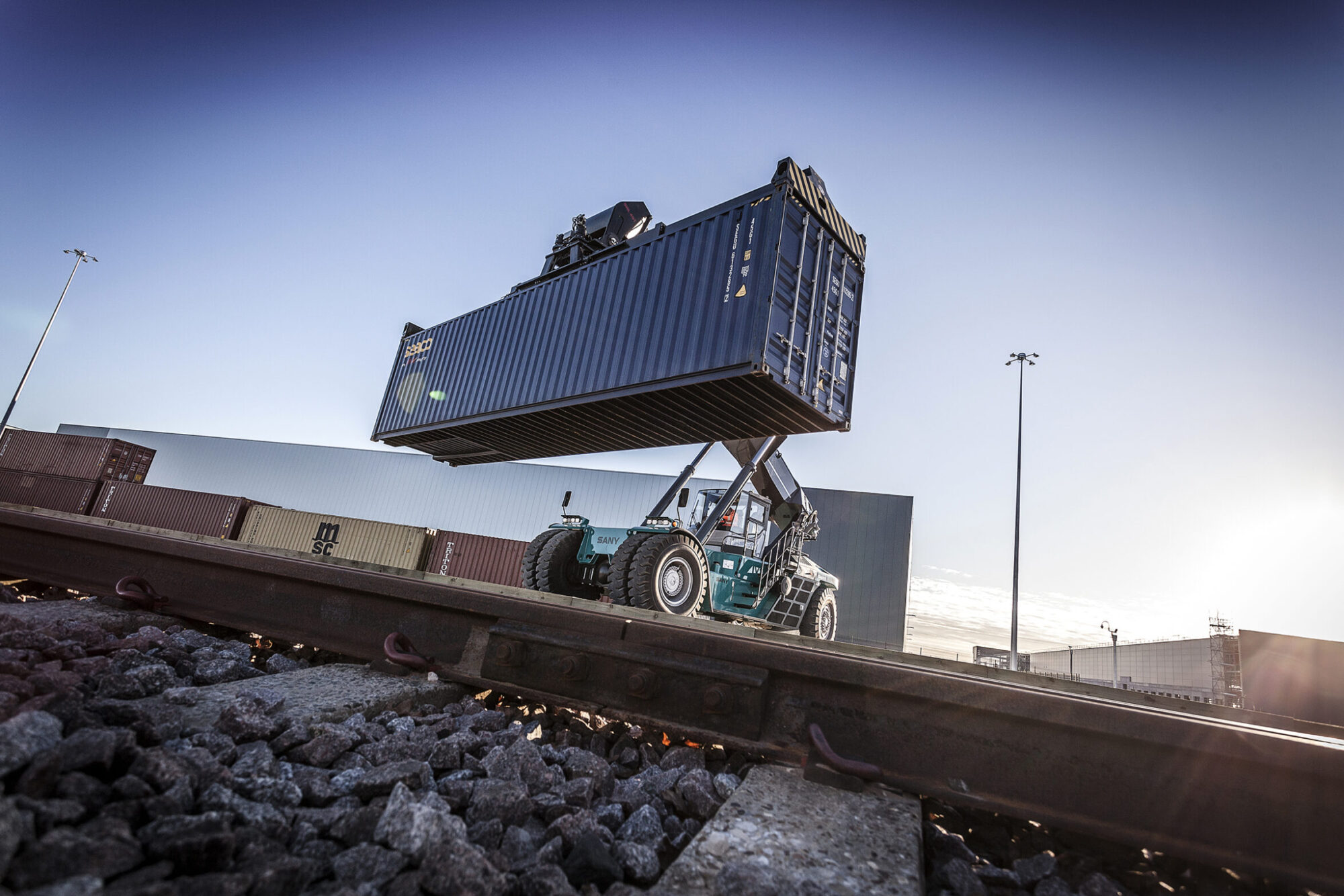 dramatic image of reach stacker with shipping container by rail lines at the new Doncaster i-port terminal
