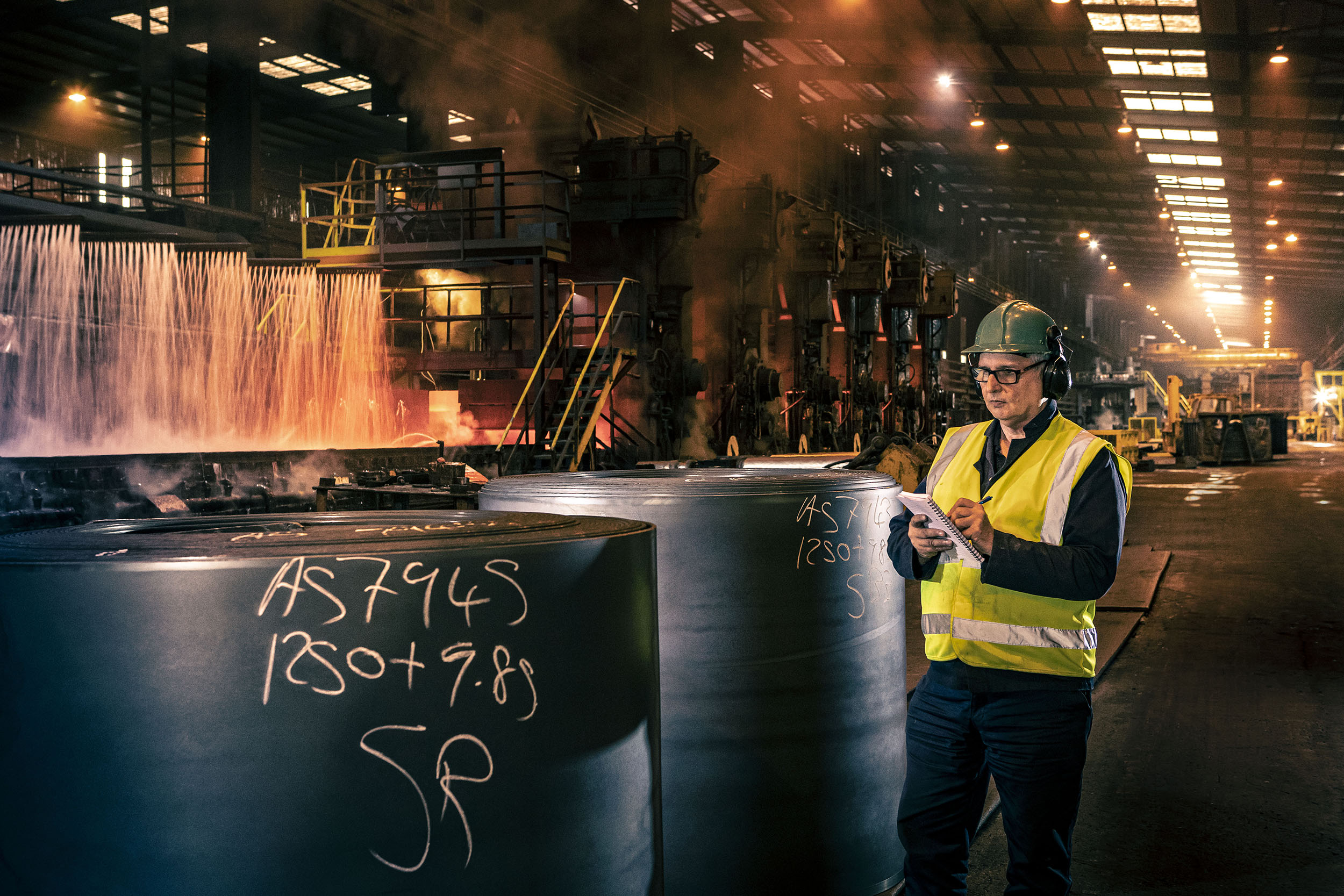 A man checking stock of steel coils in factory at Liberty Steel Newport Wales