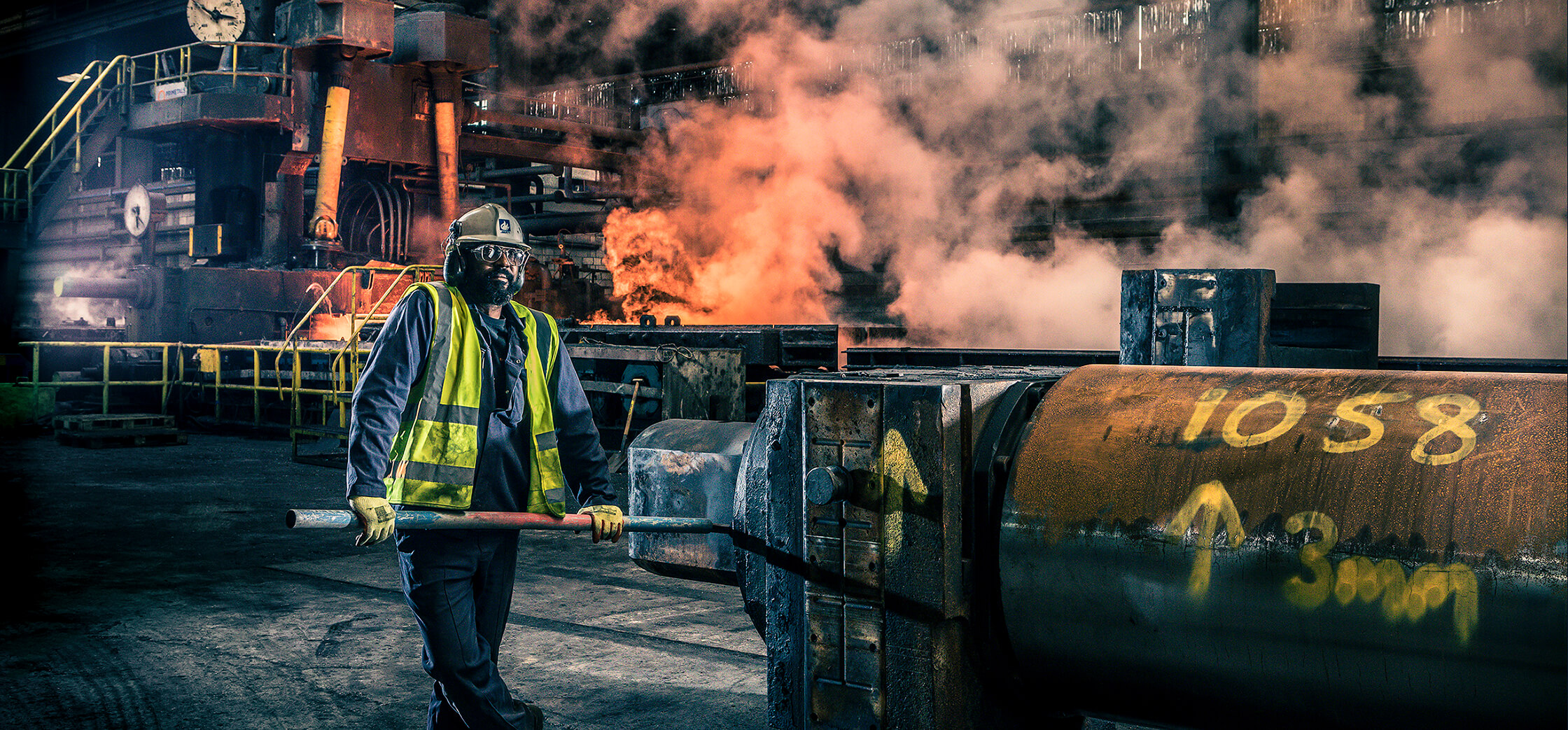 Hot rolled steel plant with Worker in front of flames and smoke billowing from process at Liberty Steel Newport