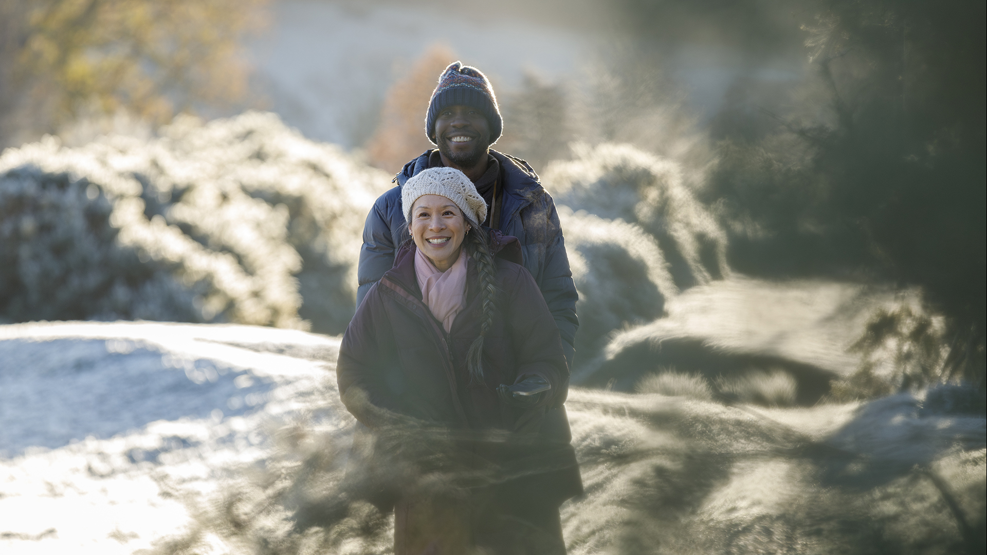 couple walking through snow and frost at Braithwaite caravan site in fantastic winter sun
